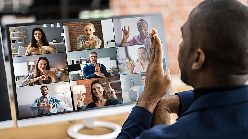 deaf man signing to coworkers on a pc